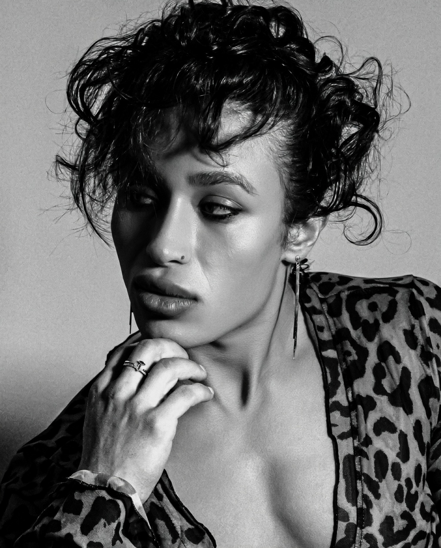 Tiffany Sam, photographed in black and white, looking slightly aside with a hand at her chin.